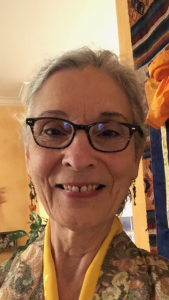 Image of Latinx woman with short gray hair and dark glasses, wearing a floral top.