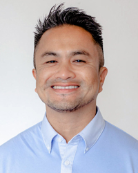Filipinx person with short dark hair, smiling and wearing a light blue collared shirt